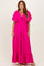 woman wearing a bright pink maxi dress with flutter sleeves and tie detail at the neckline