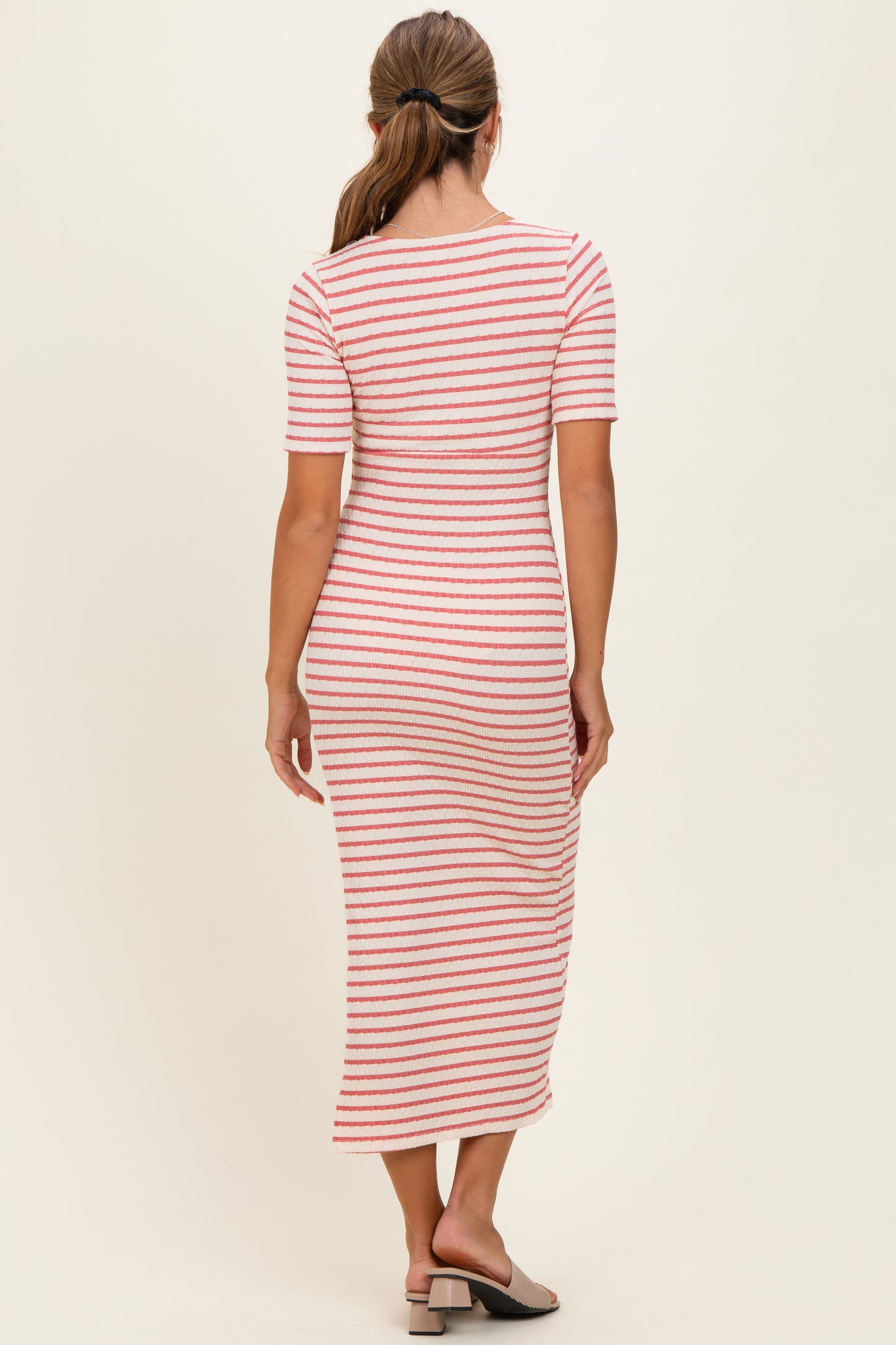 woman wearing a striped midi dress with half sleeves and a fitted silhouette, standing with her back to the camera