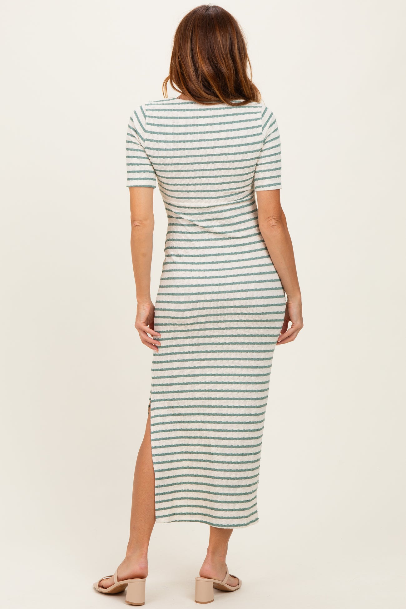 woman wearing a striped midi dress with short sleeves and a side slit, viewed from the back