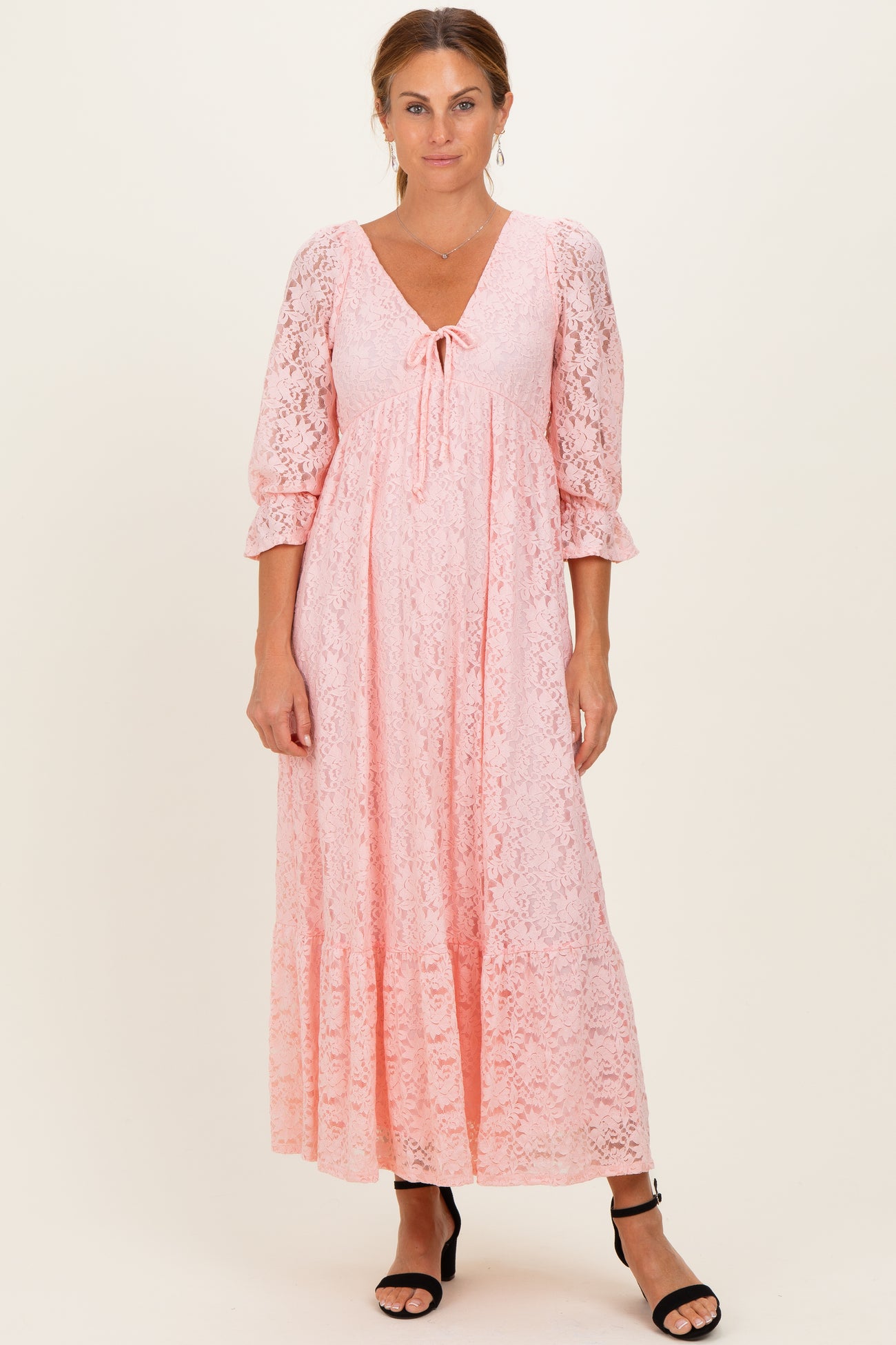 woman wearing a pink lace maxi dress with three-quarter sleeves and a tie-front neckline