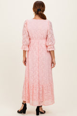 woman wearing a light pink lace maxi dress with puff sleeves and a tiered hem, viewed from the back