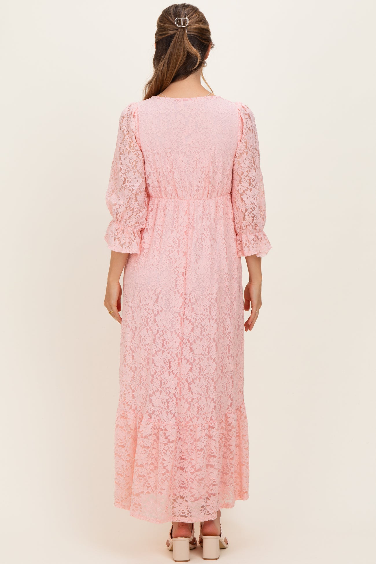 woman wearing a pink lace maternity maxi dress with three-quarter sleeves and a flowing skirt from the back