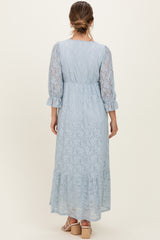 woman wearing a light blue maternity lace maxi dress with three-quarter sleeves and a tiered skirt, showing the back view