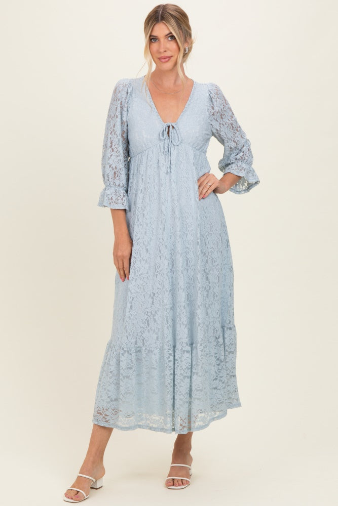 woman wearing a light blue lace maxi dress with 3/4 sleeves and a tie detail at the neckline