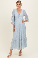 woman wearing a light blue lace maxi dress with 3/4 sleeves and a tie detail at the neckline