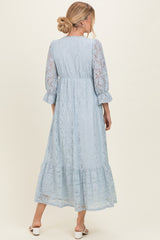woman wearing a light blue lace maxi dress with three-quarter sleeves and a tiered hem, shown from the back