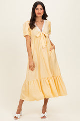 woman wearing a yellow polka dot midi dress with puff sleeves and a v-neckline tie detail