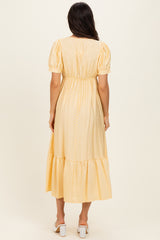 woman wearing a yellow polka dot midi dress with puff sleeves and a tiered hem, seen from the back