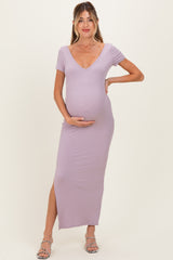 woman wearing a lavender maternity maxi dress with a deep v-neck and a side slit, gently cradling her baby bump