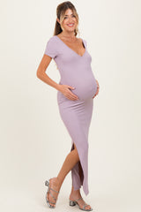 woman wearing a light lavender short sleeve maternity dress with a deep v-neck and side slit, cradling her baby bump