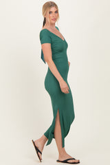 woman wearing a green fitted maxi dress with a deep v-neck and side slits, styled with sandals