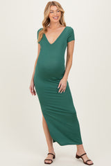 woman wearing a deep green maternity maxi dress with a v-neck and side slit, showing her baby bump