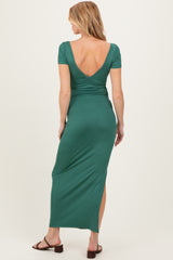 woman wearing a green maternity maxi dress with a deep v-back and side slits