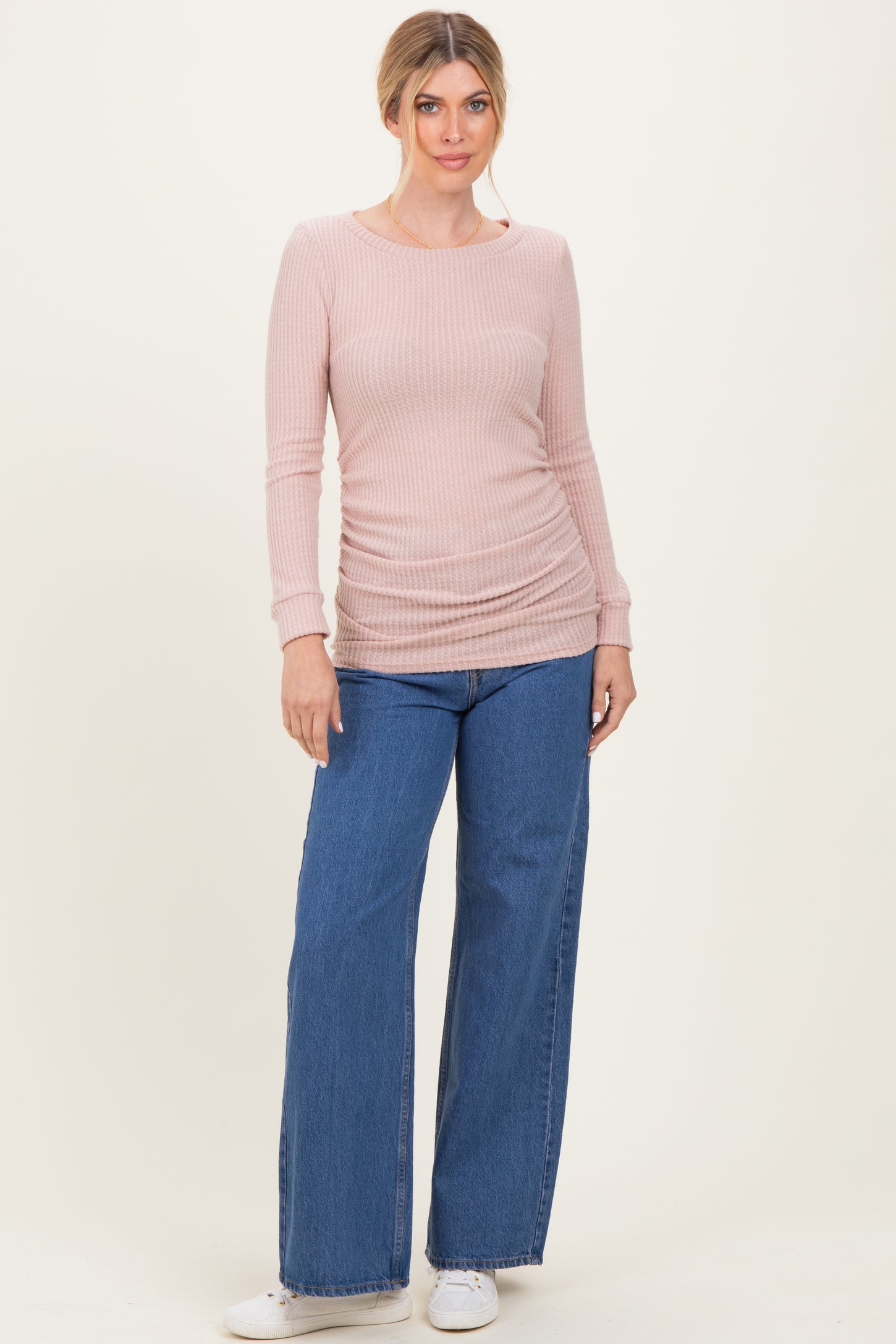 woman wearing a light pink ribbed long sleeve top with side ruching and wide leg denim jeans