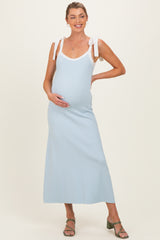 woman wearing a light blue maternity maxi dress with white straps and holding her baby bump