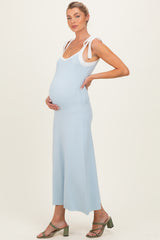woman wearing a light blue maternity dress with white shoulder ties, showing her baby bump
