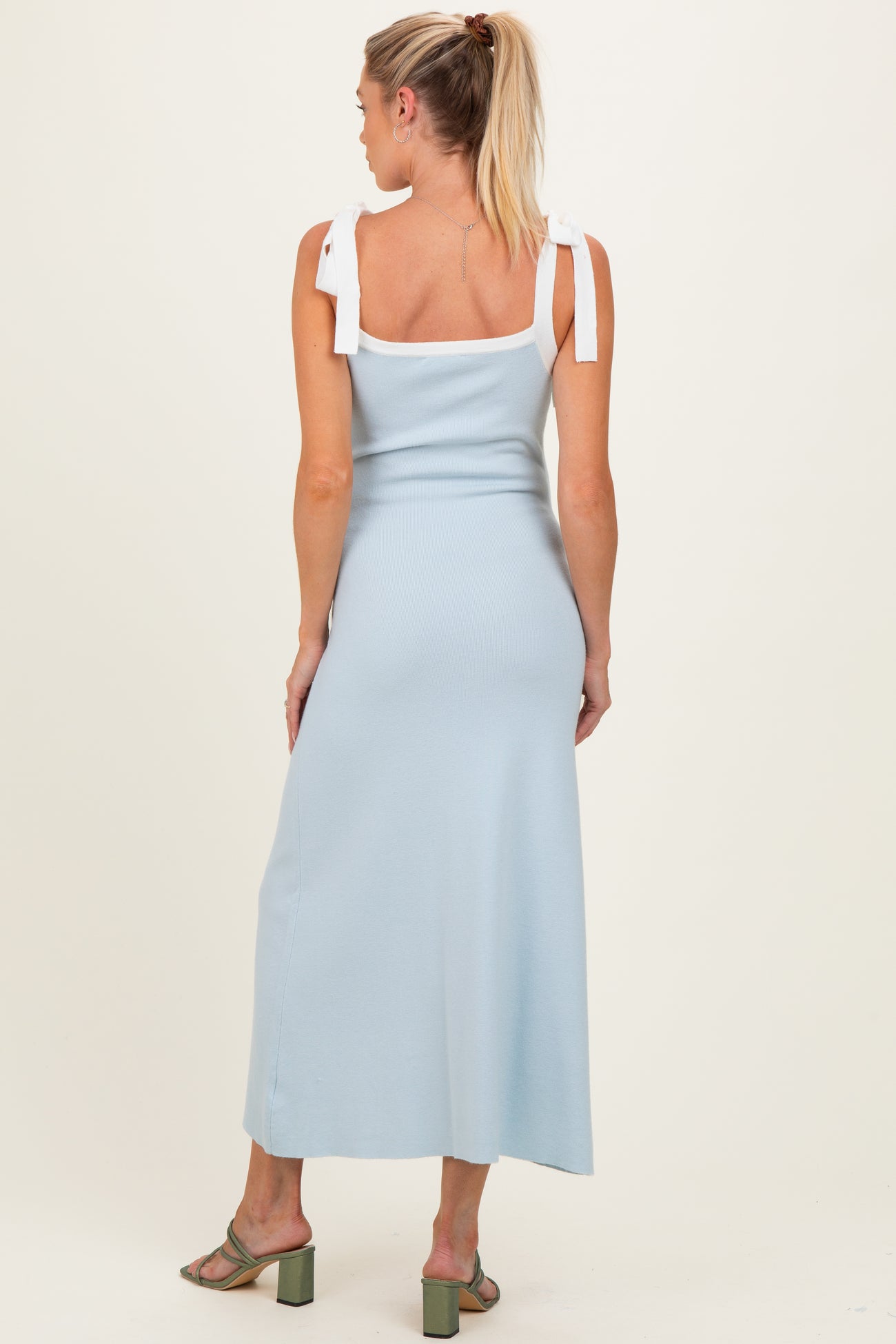 woman wearing a light blue maternity maxi dress with tie straps and a fitted silhouette, seen from the back