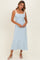 woman wearing a light blue ribbed midi dress with white tie straps and heeled sandals