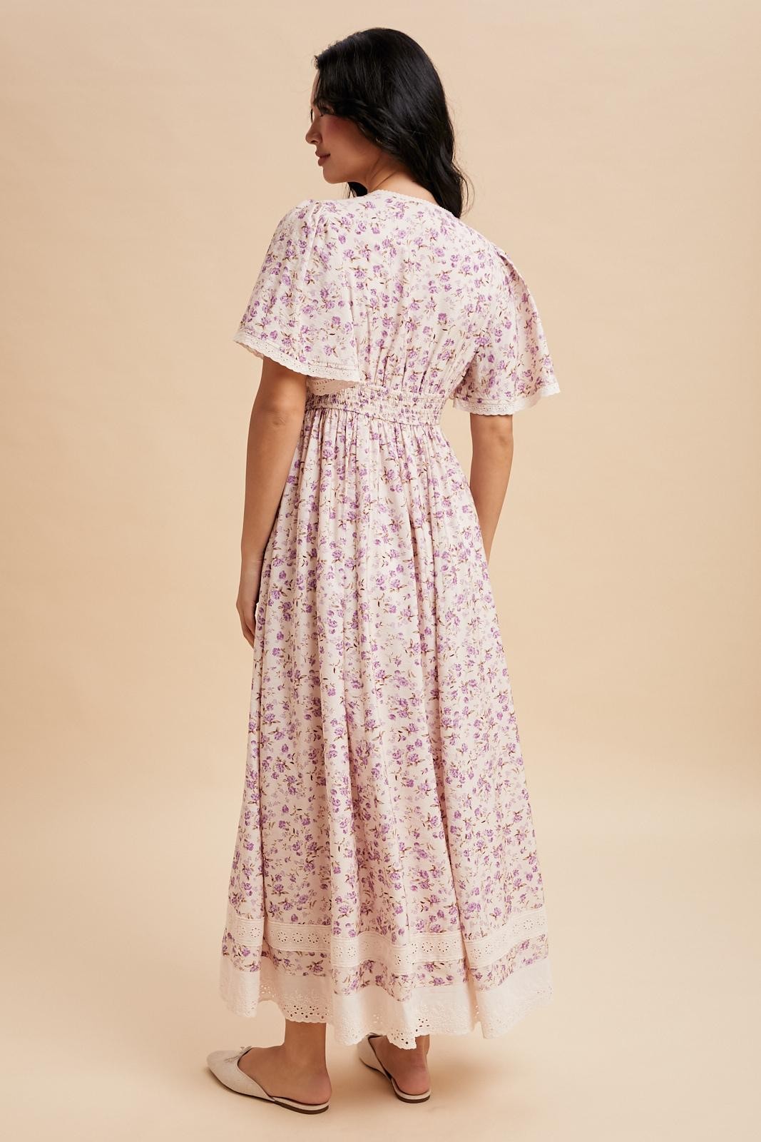 woman wearing a back view of a floral maxi dress with short flutter sleeves and a cinched waist