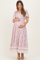 woman wearing a floral print maternity maxi dress with short sleeves and a v-neck, holding her baby bump