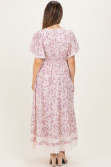 woman wearing a floral print pink maternity dress with short sleeves and a fitted waist, showing a baby bump from the back