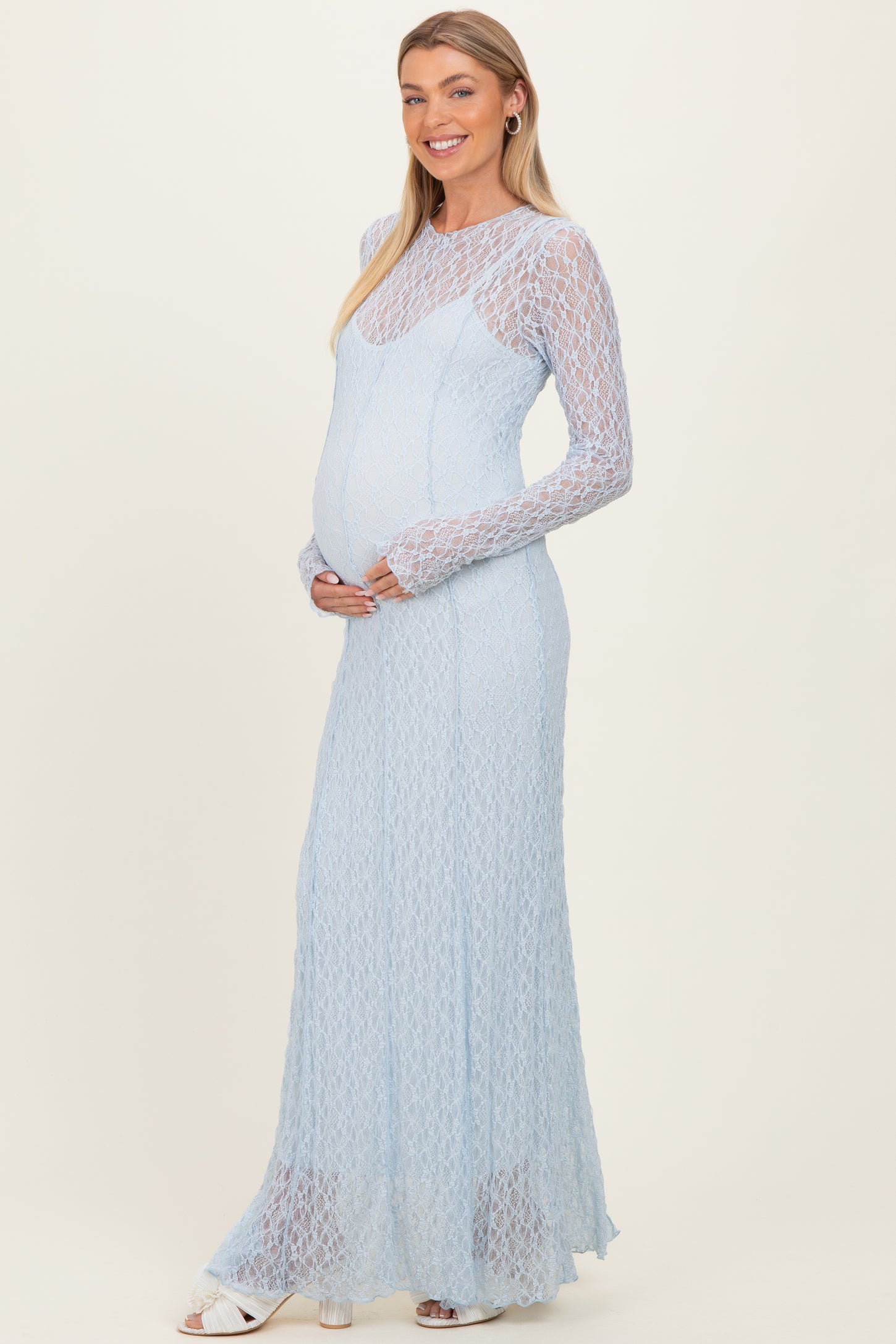 woman wearing a light blue lace maternity gown with long sleeves and a visible baby bump