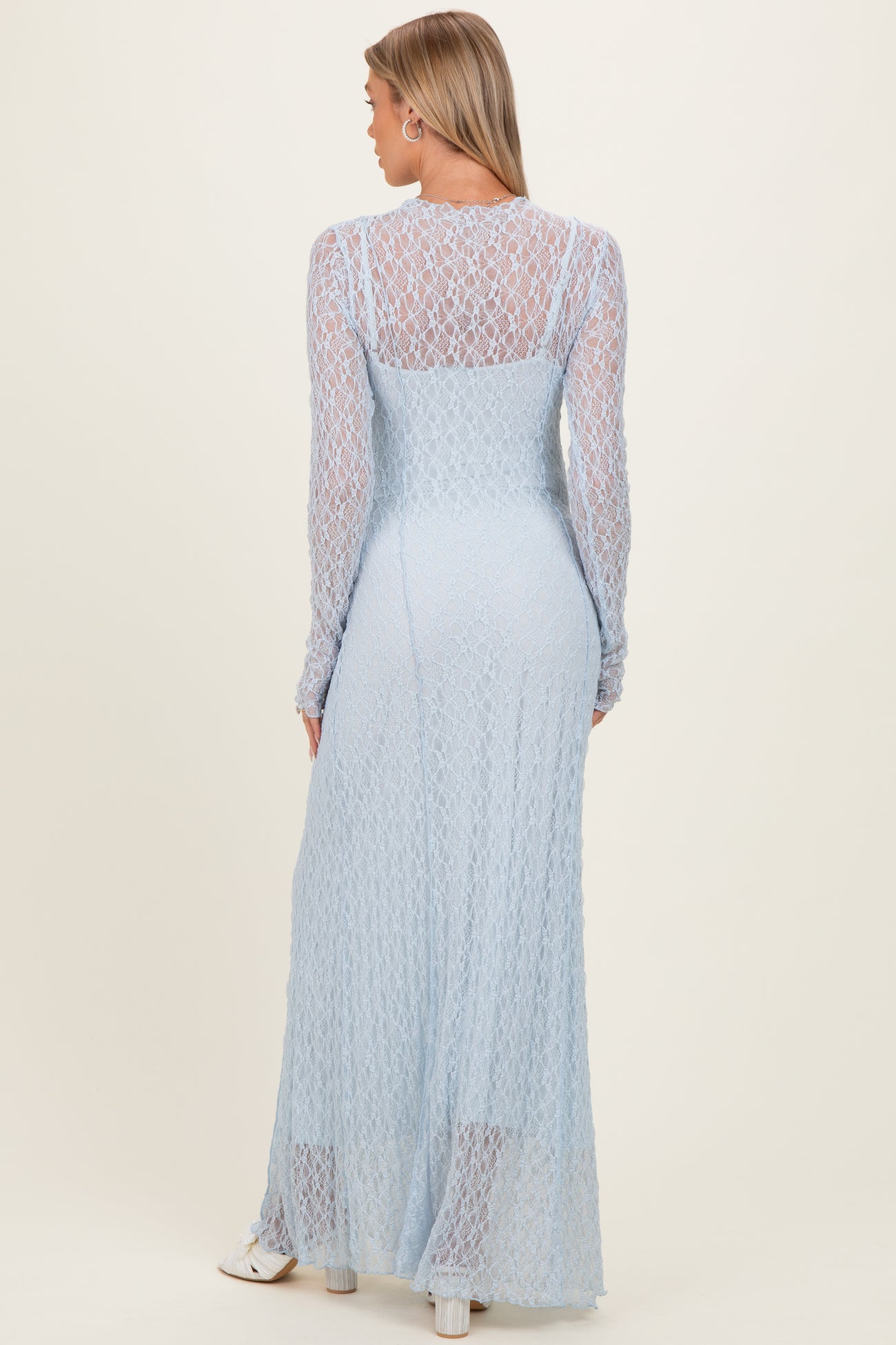 woman wearing a light blue long sleeve maternity dress with intricate lace detailing and a flowy fit