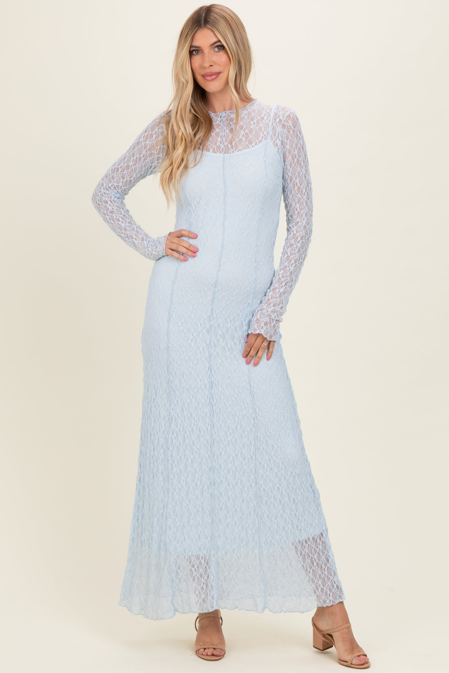 woman wearing a light blue long sleeve maxi dress with a lace overlay and a fitted silhouette