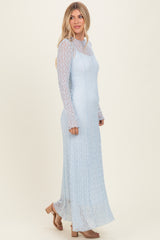 woman wearing a light blue long sleeve lace maxi dress with a fitted bodice and flared hem, styled with open-toed sandals