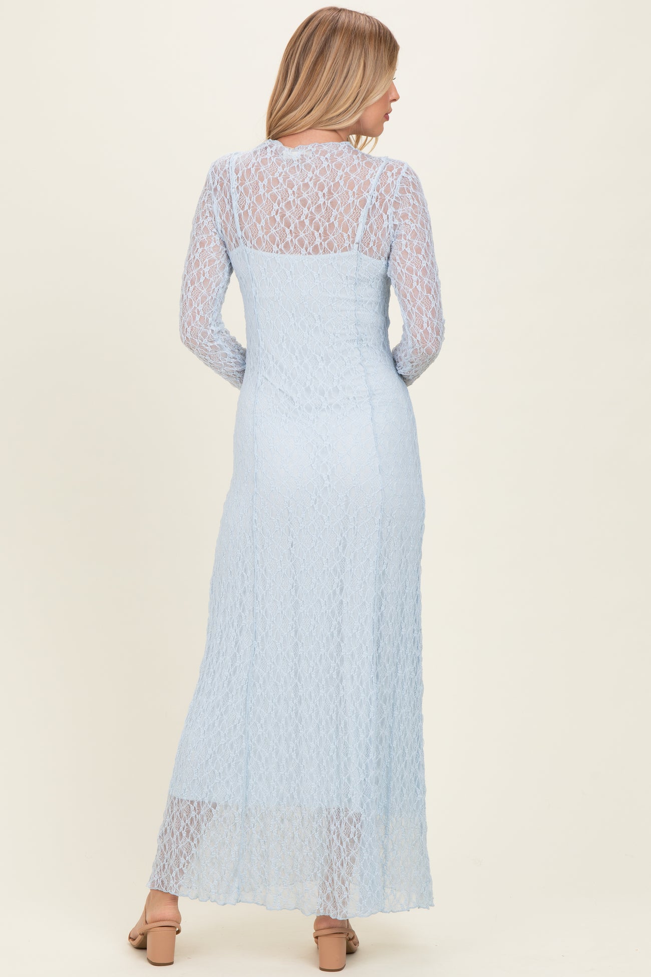 woman wearing a light blue lace long sleeve maxi dress with a fitted bodice and flowing skirt from the back