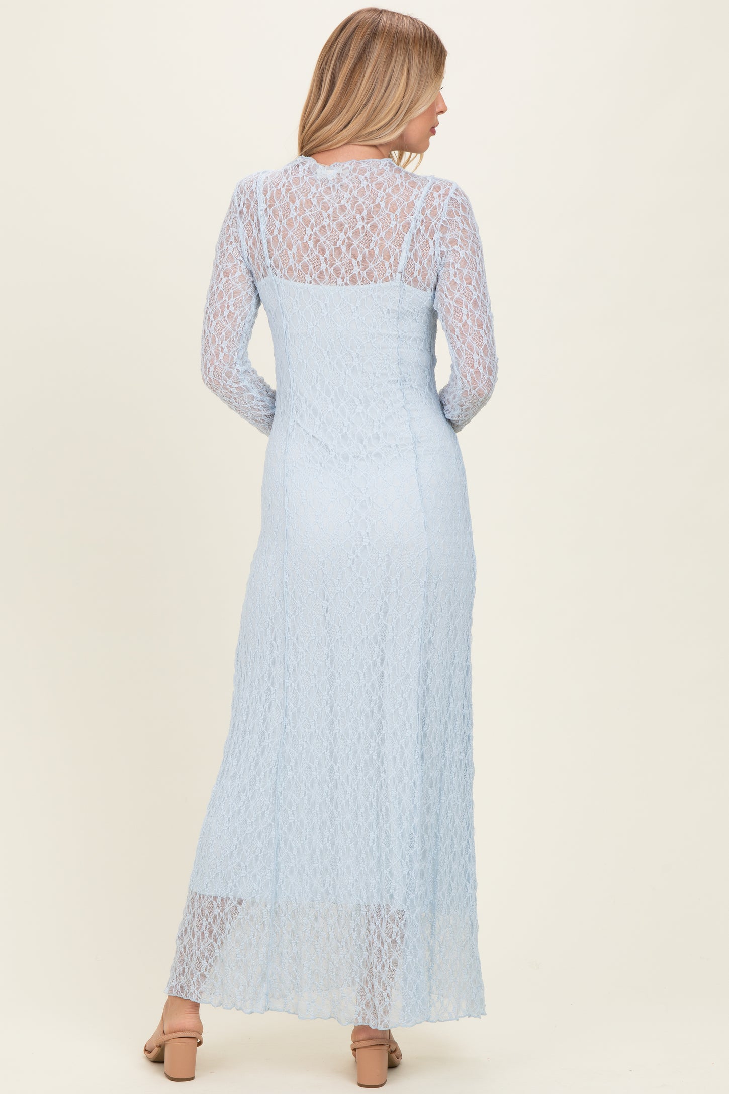 woman wearing a light blue lace long sleeve maxi dress with a fitted bodice and flowing skirt from the back