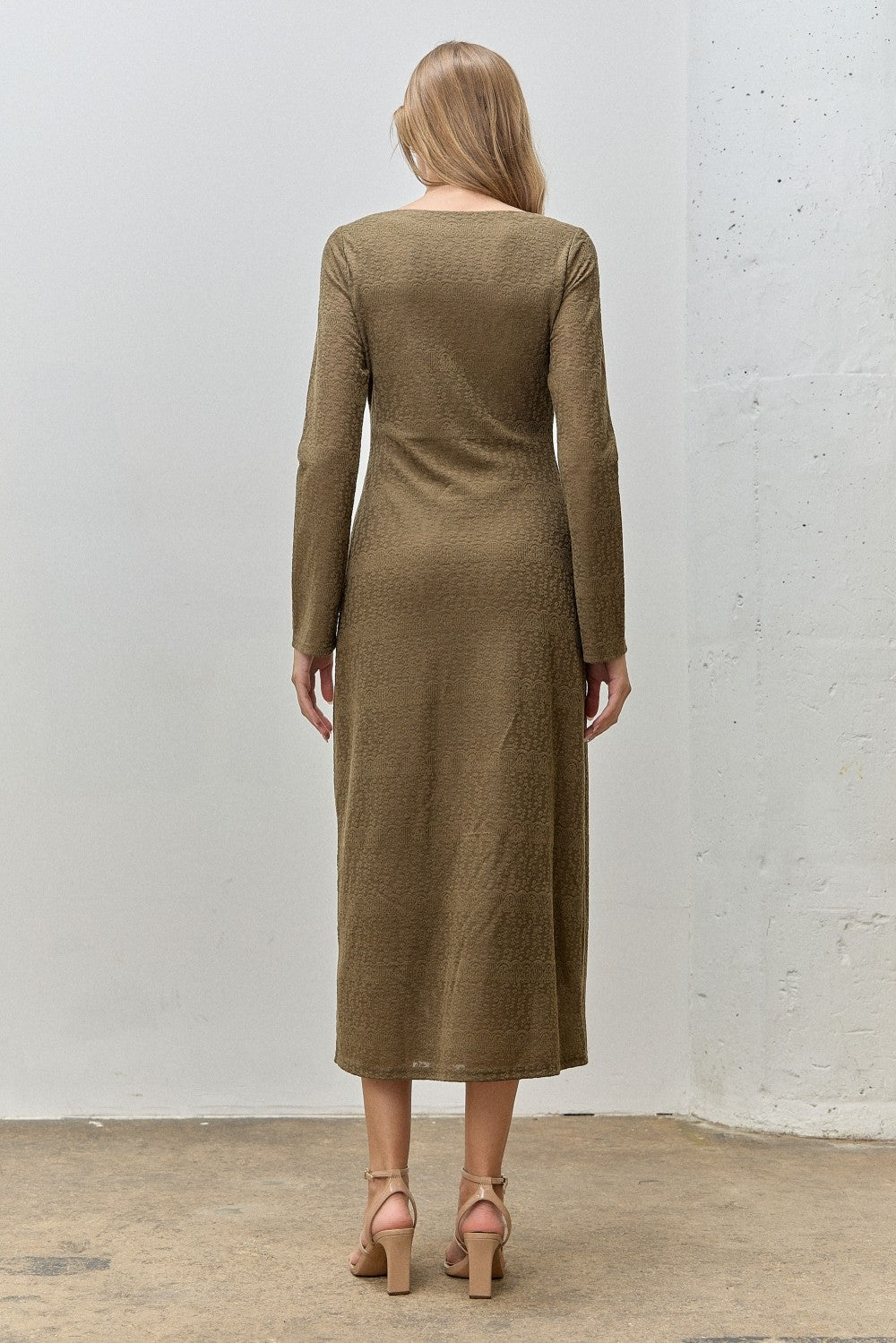 woman wearing a long sleeve olive green midi dress, shown from the back, styled with high-heeled sandals