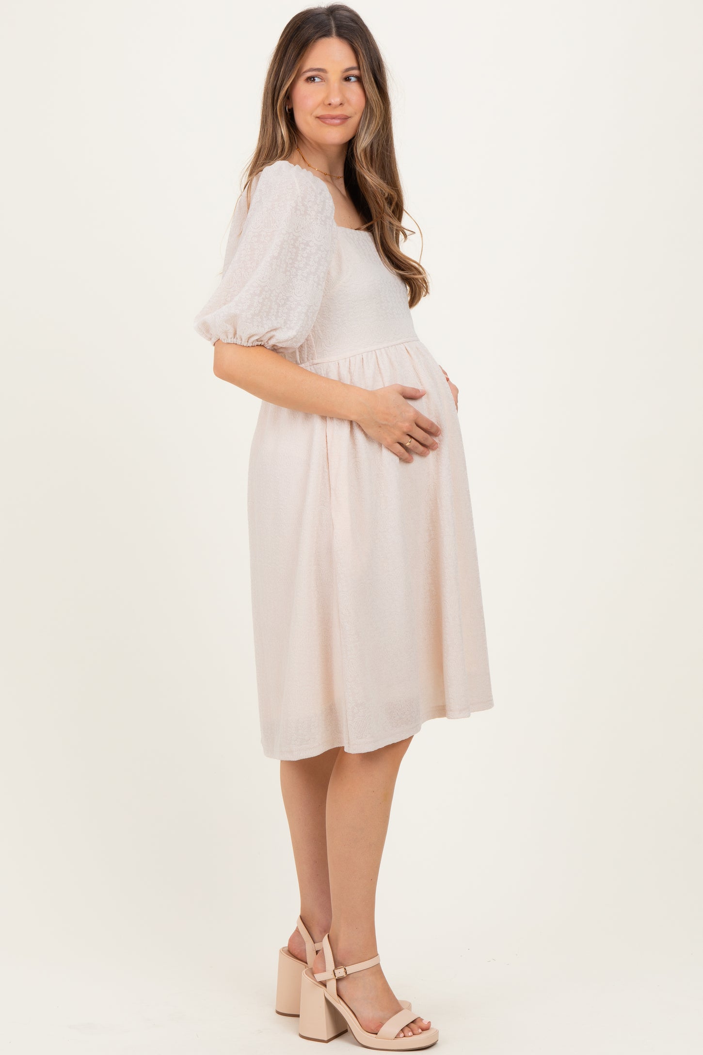woman wearing a light pink maternity dress with puff sleeves and a baby bump visible