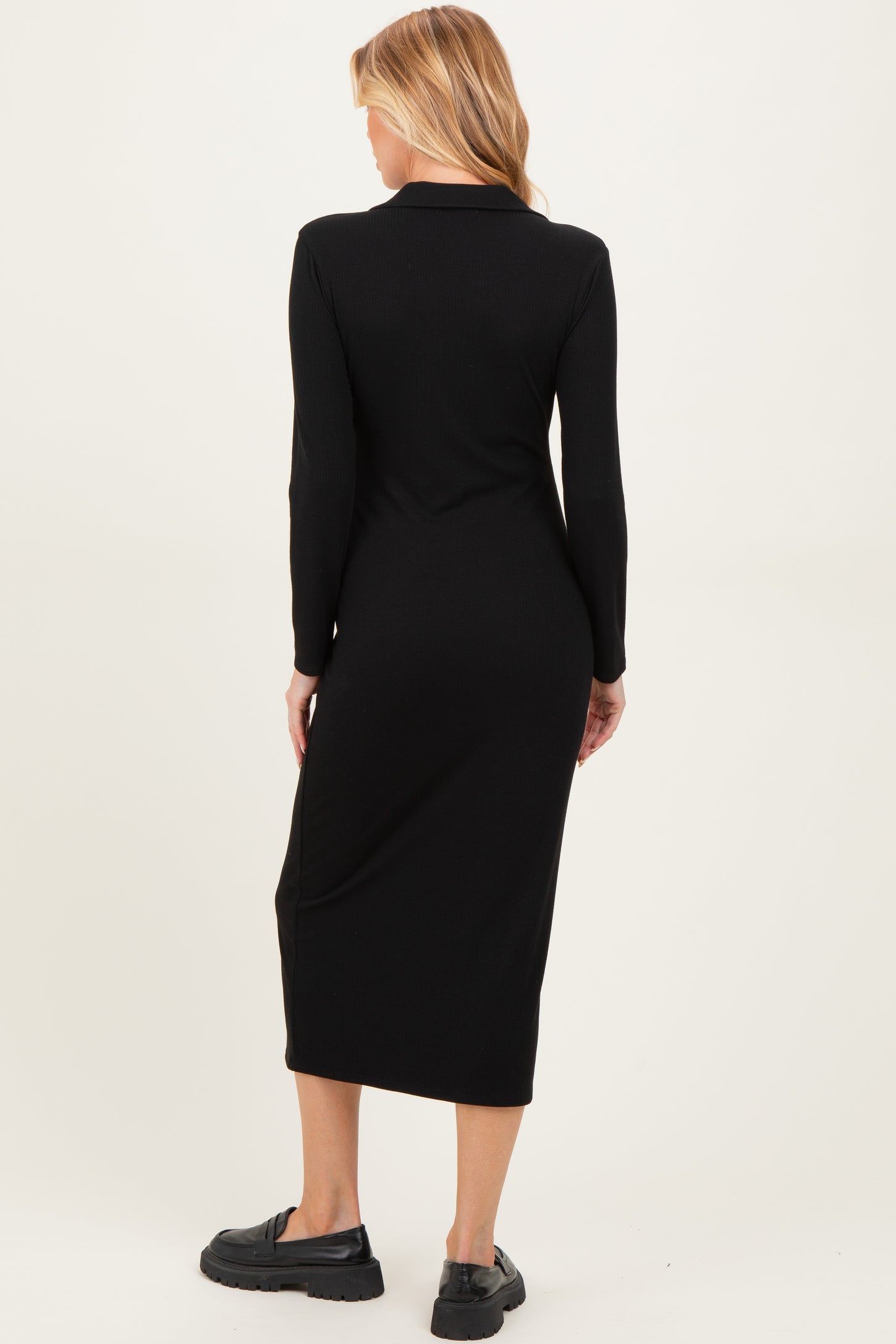 woman wearing a long sleeve black maternity dress with a midi length and a fitted silhouette from the back