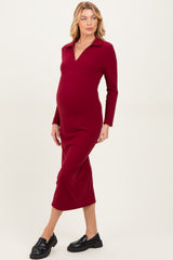 woman wearing a burgundy long sleeve maternity dress with a collared neckline and a visible baby bump