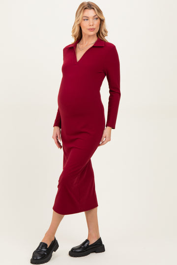 woman wearing a burgundy long sleeve maternity dress with a collared neckline and a visible baby bump