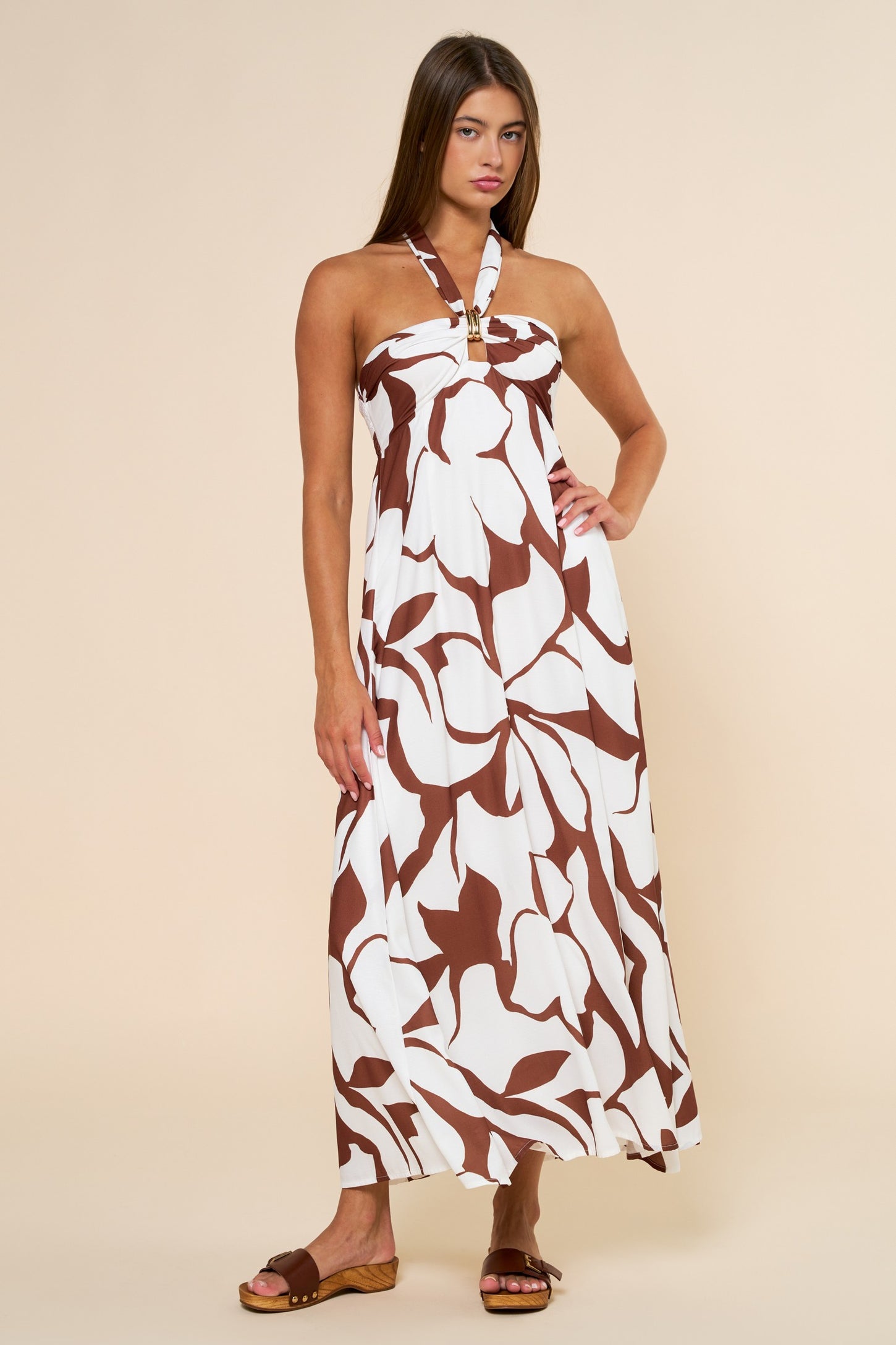 woman wearing a brown and white halter neck maxi dress with a floral pattern