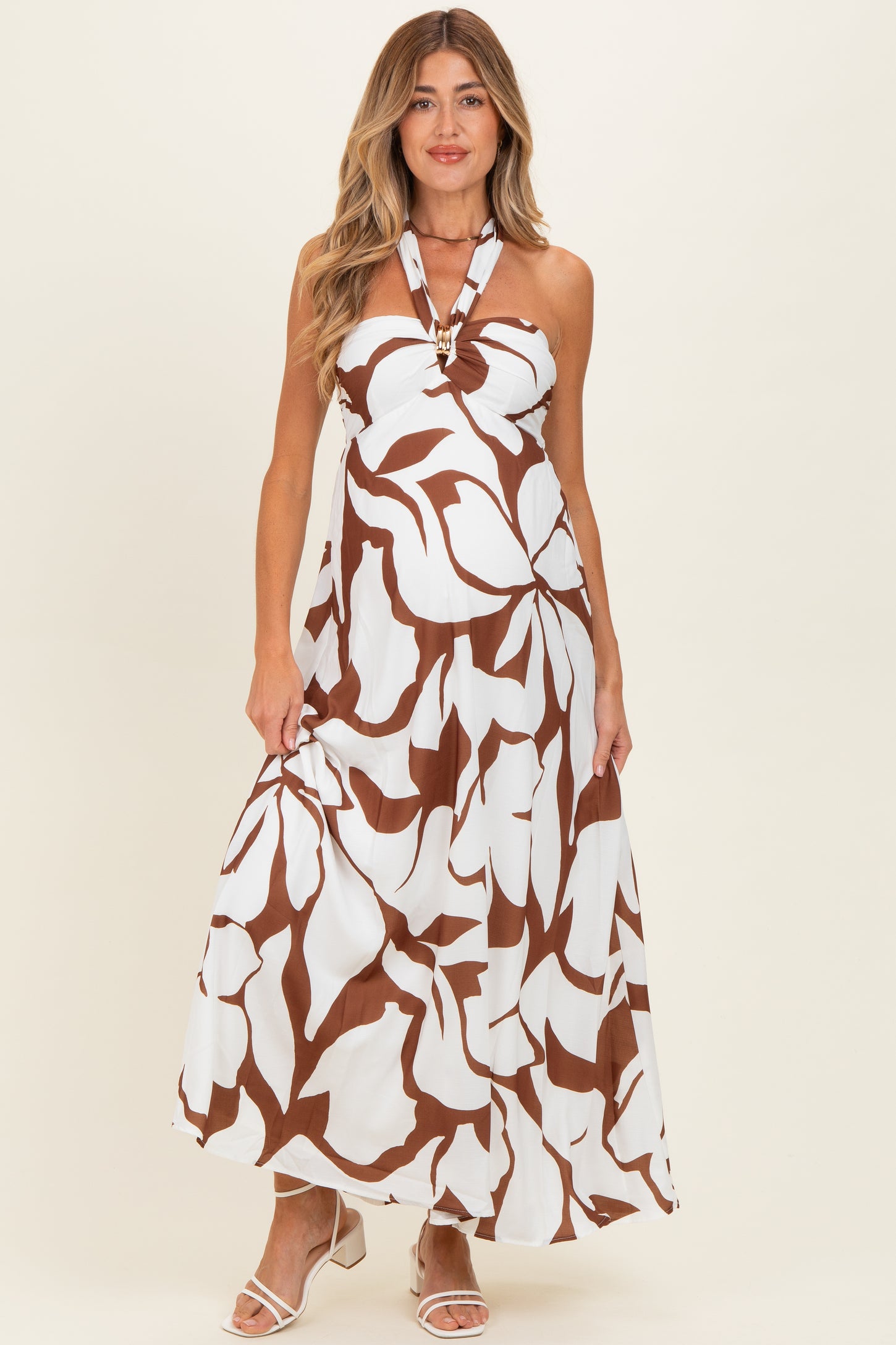 woman wearing a white maternity maxi dress with brown floral print and halter neck detail, and baby bump visible