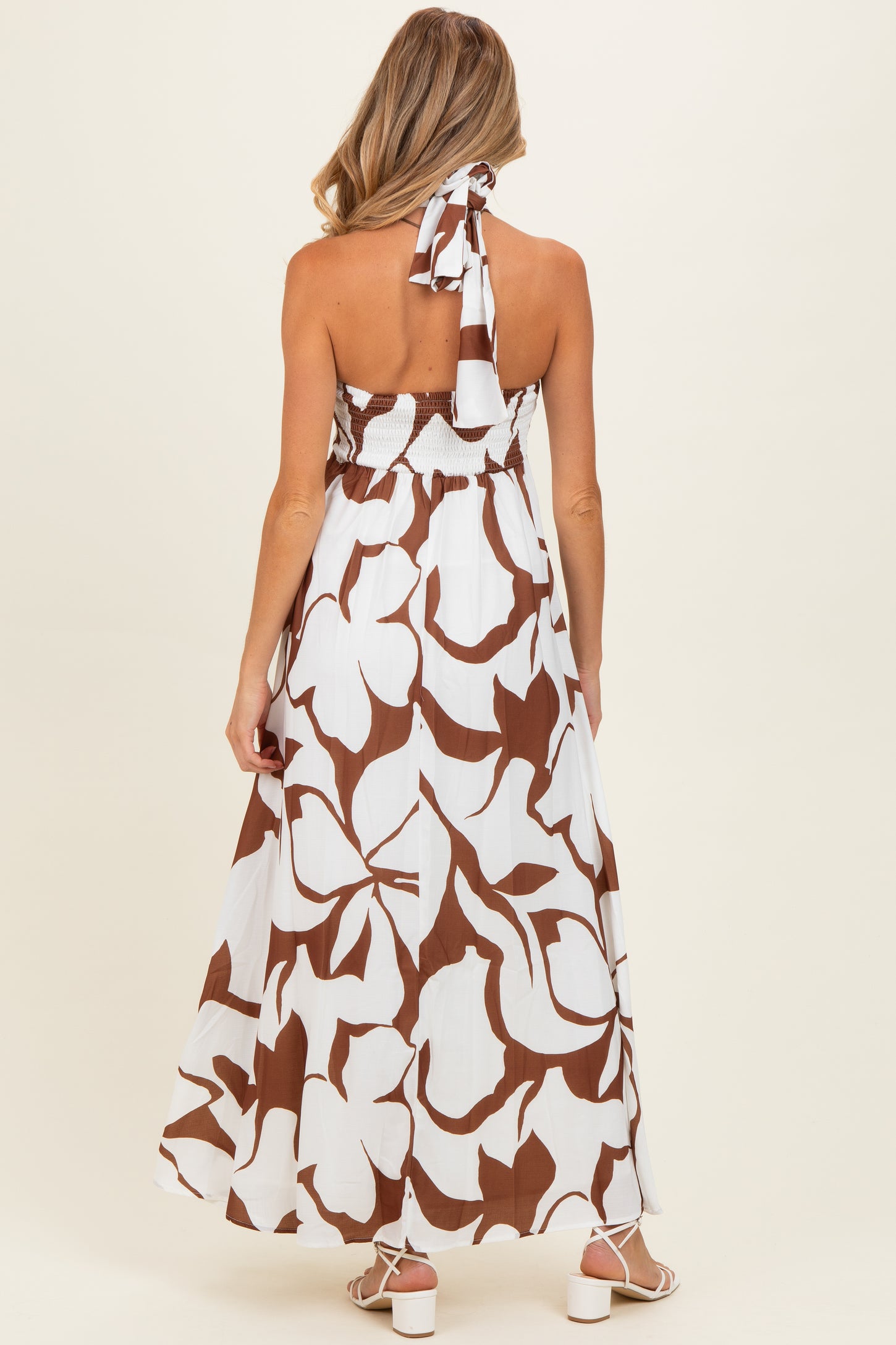 woman wearing a brown and white floral maxi maternity dress with a halter tie and smocked bodice