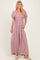 woman wearing a purple floral maxi dress with square neckline and puff sleeves, standing with hands in pockets