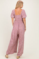 woman wearing a pink floral backless jumpsuit with puff sleeves and wide-leg pants