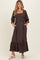 woman wearing a brown floral maternity dress with square neckline and puff sleeves, featuring pockets and a ruffled hem