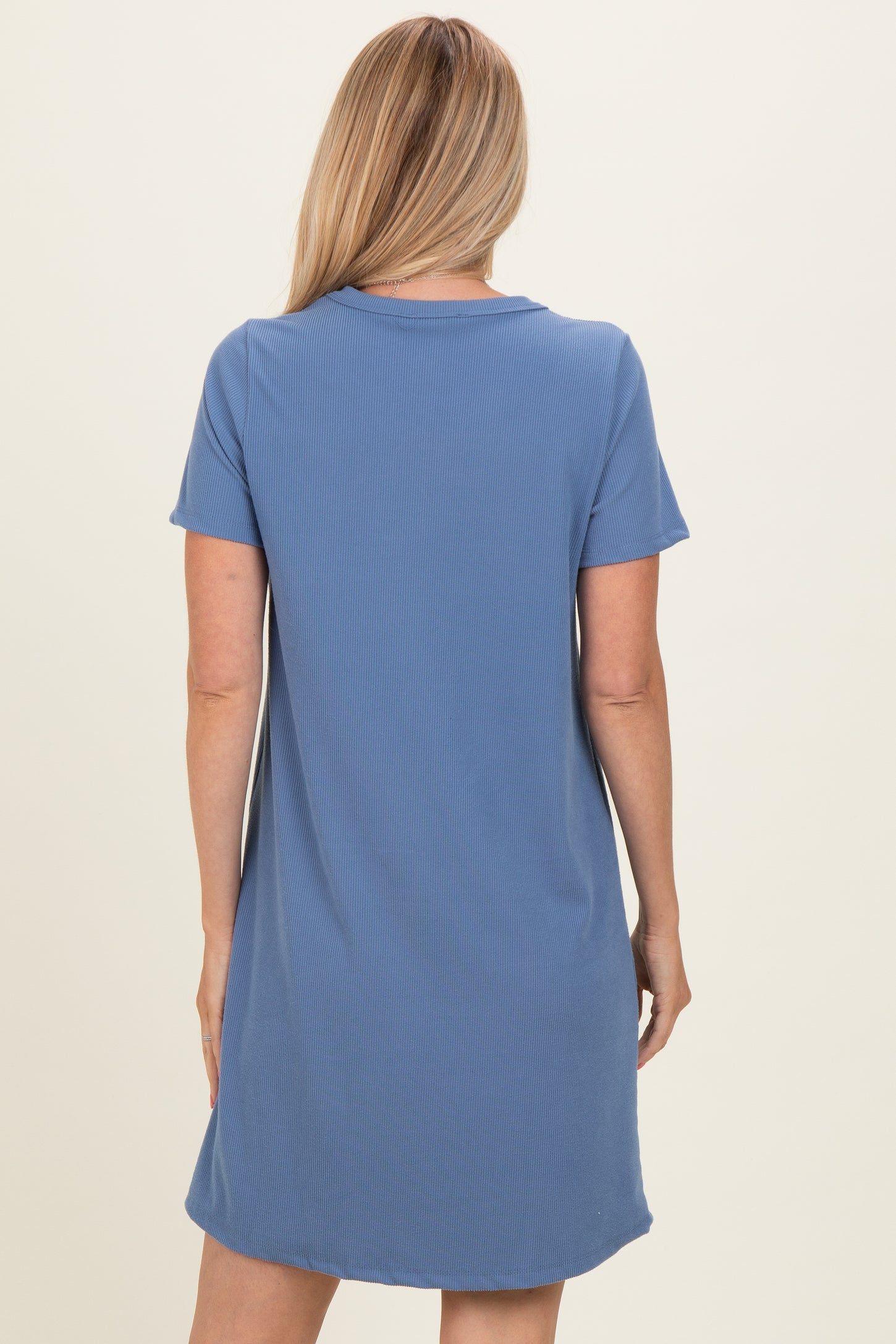woman wearing a short sleeve blue ribbed dress, seen from the back