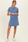 woman wearing a blue short sleeve maternity dress, standing and smiling, with a relaxed fit and ribbed texture