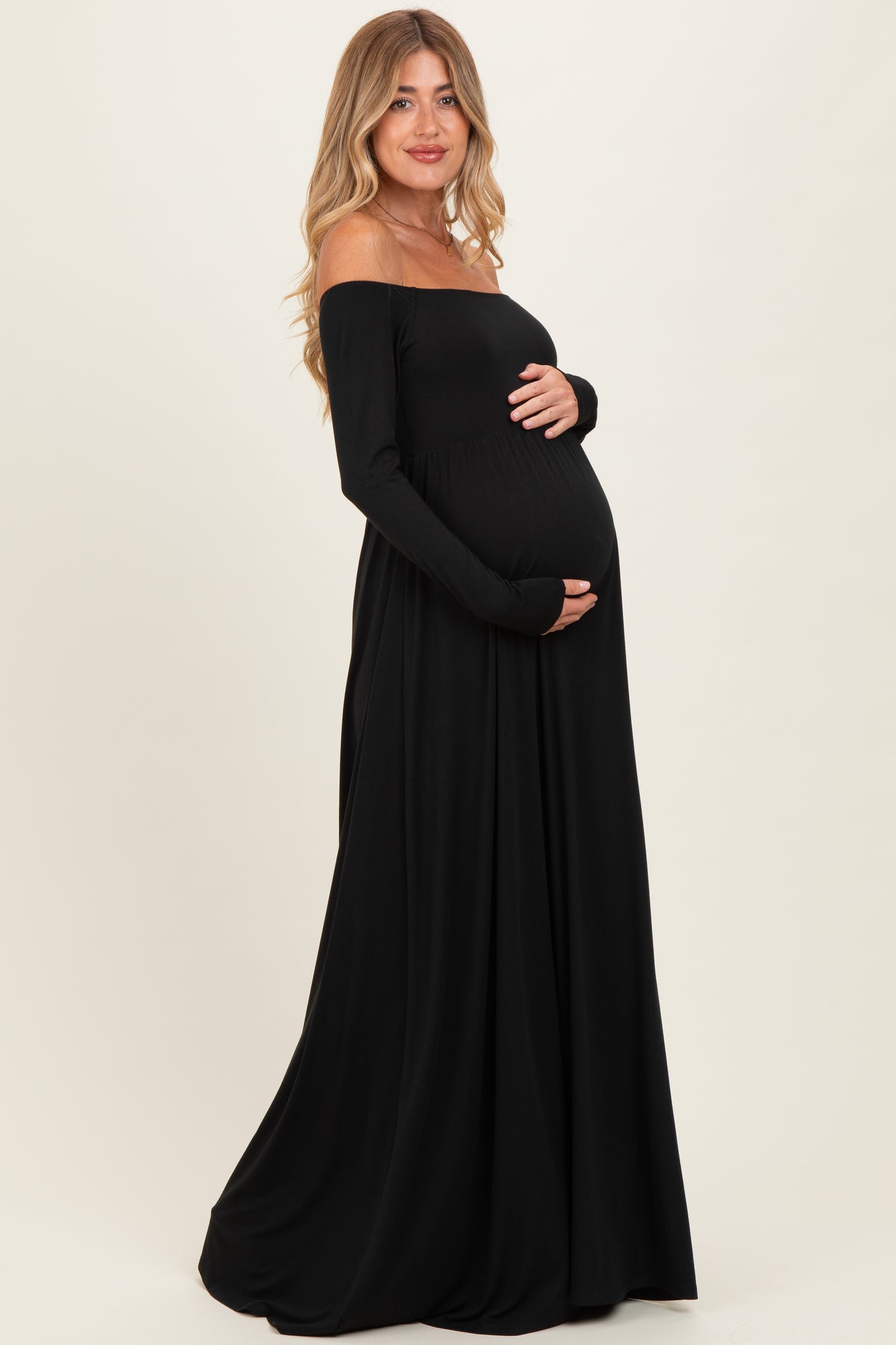woman wearing a black off-shoulder maternity gown and holding her baby bump