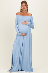 woman wearing a light blue off-the-shoulder maternity maxi dress and holding her baby bump