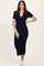 woman wearing a navy blue ribbed midi dress with pink trim and short sleeves, paired with white sneakers