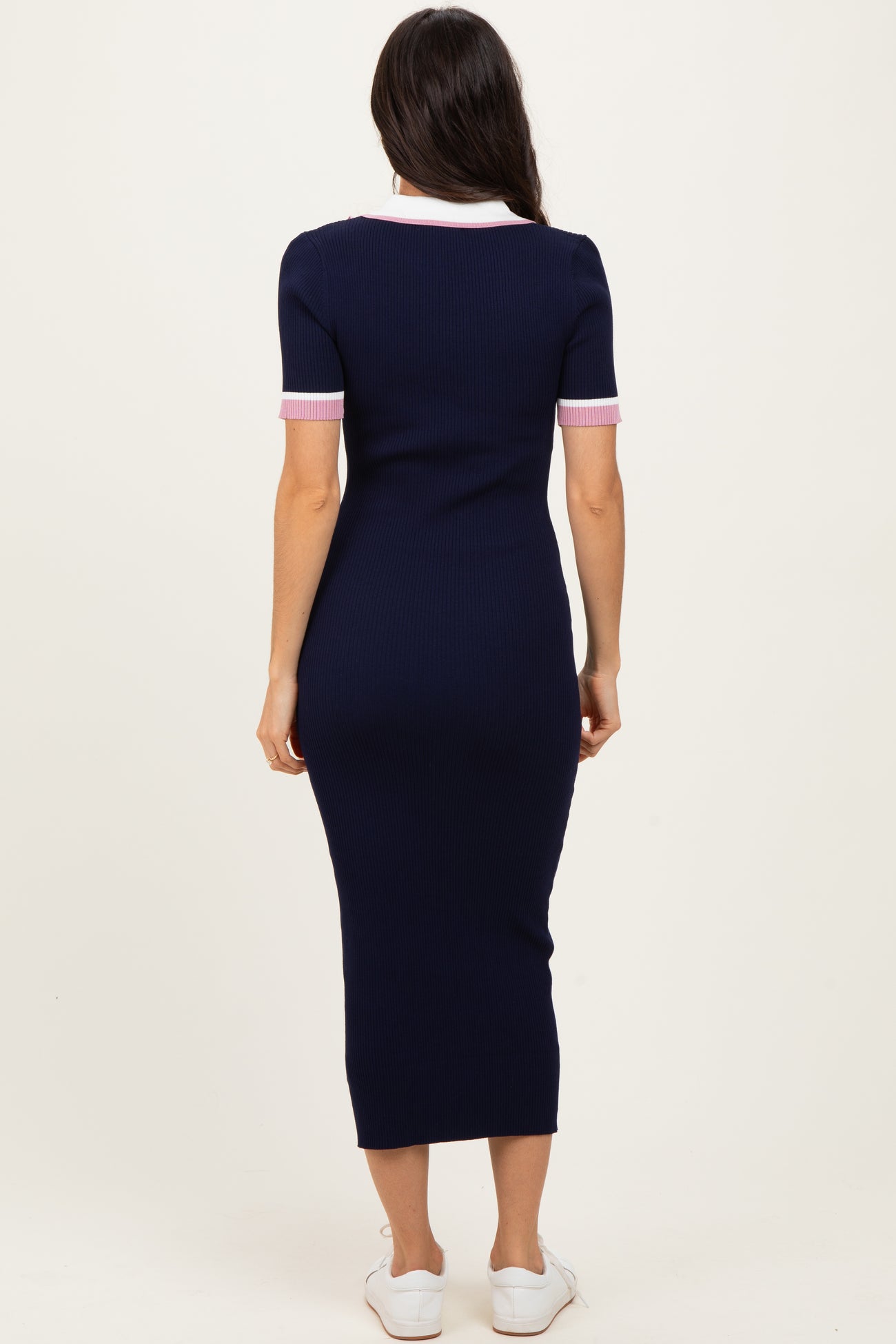 woman wearing a navy ribbed midi dress with pink striped short sleeves and a white collar, viewed from the back