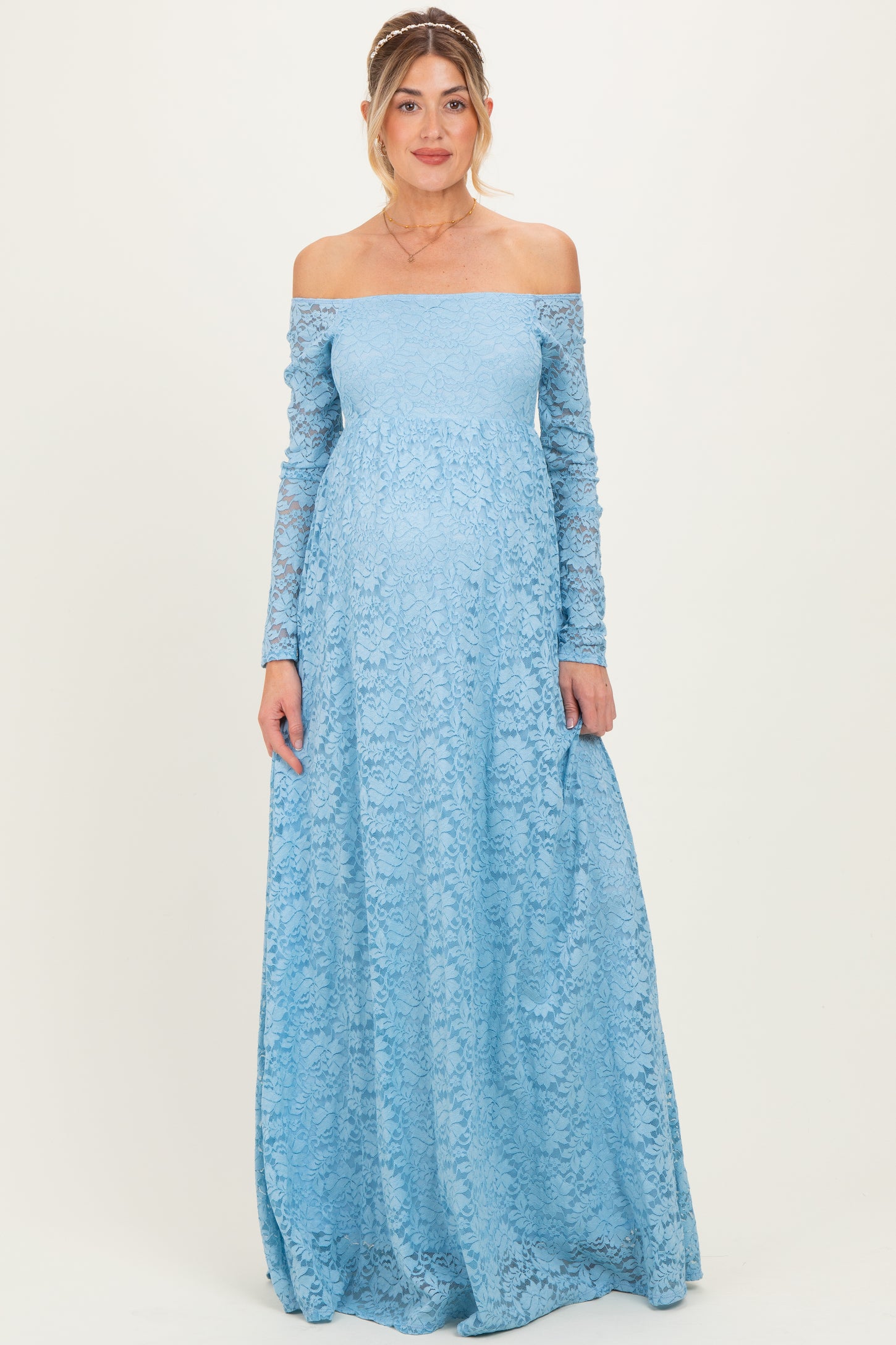 woman wearing a light blue off-the-shoulder lace maternity dress with long sleeves and a visible baby bump