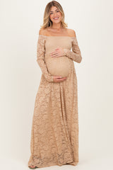 woman wearing a beige lace off-shoulder maternity gown and holding her baby bump